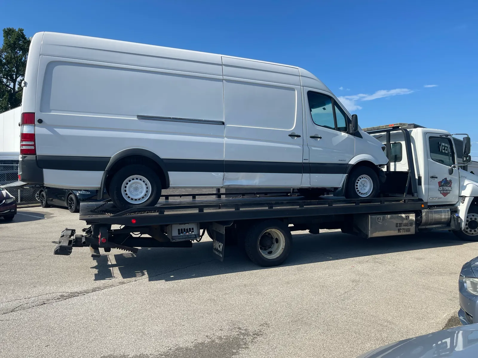 Joe Towing flatbed carrying a white cargo van.